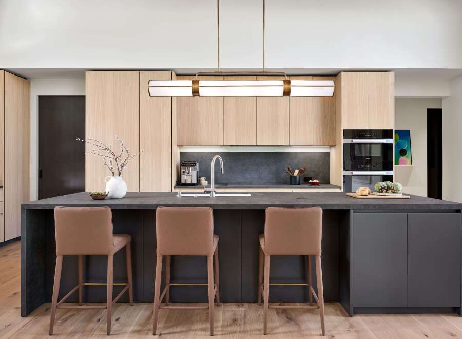 Experience modern luxury in this stunning kitchen, featuring sleek light wood cabinetry and a spacious dark stone island perfect for entertaining.
