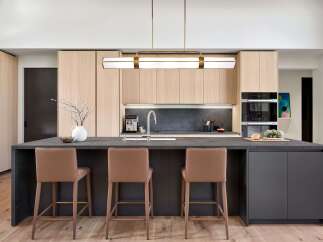 Experience modern luxury in this stunning kitchen, featuring sleek light wood cabinetry and a spacious dark stone island perfect for entertaining.