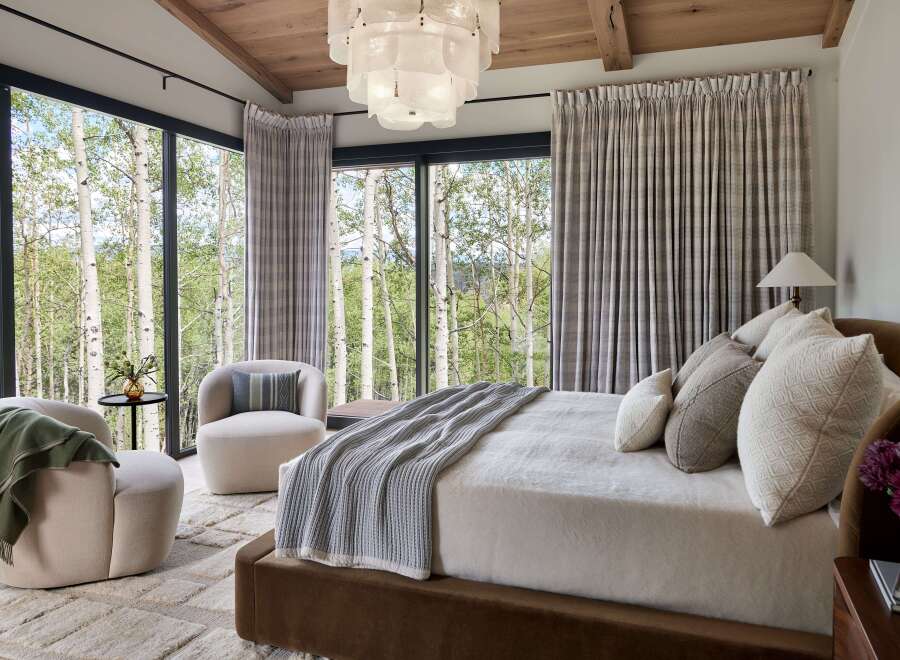 Experience luxury mountain living in this stunning bedroom, featuring expansive windows that frame breathtaking views of aspen trees.