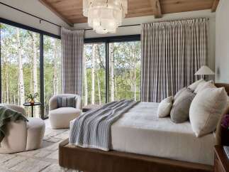 Experience luxury mountain living in this stunning bedroom, featuring expansive windows that frame breathtaking views of aspen trees.