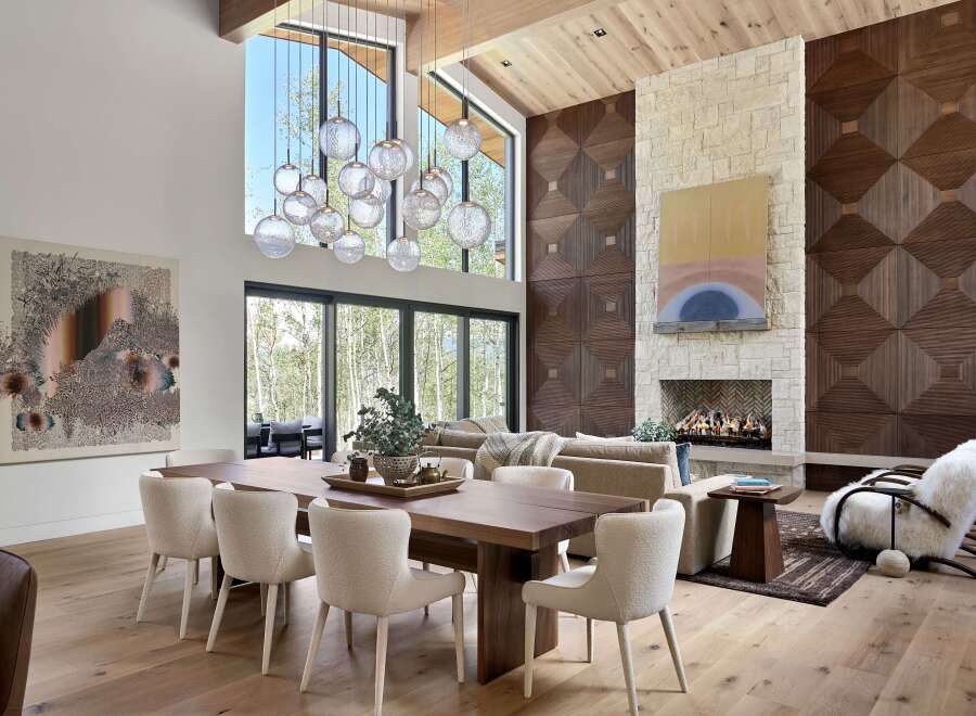 Experience luxury living in this stunning great room, featuring a soaring ceiling with exposed wood beams and a dramatic multi-tiered glass chandelier.