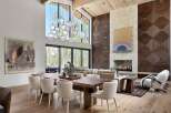 Experience luxury living in this stunning great room, featuring a soaring ceiling with exposed wood beams and a dramatic multi-tiered glass chandelier.