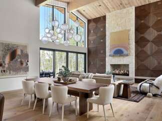 Experience luxury living in this stunning great room, featuring a soaring ceiling with exposed wood beams and a dramatic multi-tiered glass chandelier.