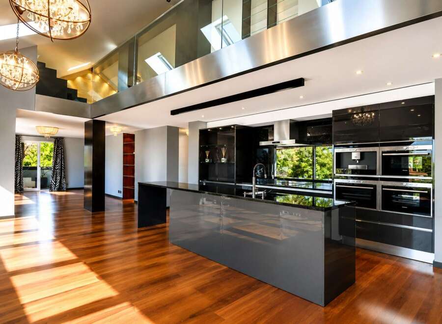 Experience luxury living in this stunning modern home featuring a sleek, open-plan kitchen with high-end appliances and a spacious island.