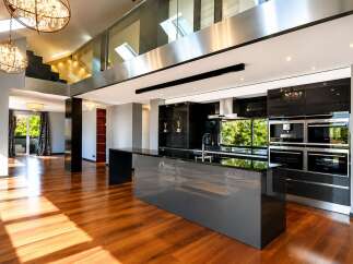 Experience luxury living in this stunning modern home featuring a sleek, open-plan kitchen with high-end appliances and a spacious island.