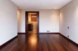 Experience modern luxury in this spacious room featuring a rich, dark hardwood floor that gleams under recessed lighting.
