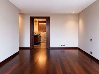 Experience modern luxury in this spacious room featuring a rich, dark hardwood floor that gleams under recessed lighting.