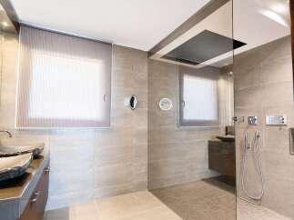 Experience modern luxury in this spacious bathroom featuring a walk-in shower with a sleek glass enclosure and a digital control panel.