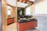 This modern bathroom features a double vanity with unique stone vessel sinks and sleek orange cabinetry.