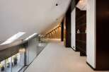 Experience modern luxury in this spacious loft-style hallway, featuring a sleek glass railing overlooking a balcony with lush greenery.