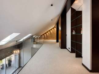 Experience modern luxury in this spacious loft-style hallway, featuring a sleek glass railing overlooking a balcony with lush greenery.
