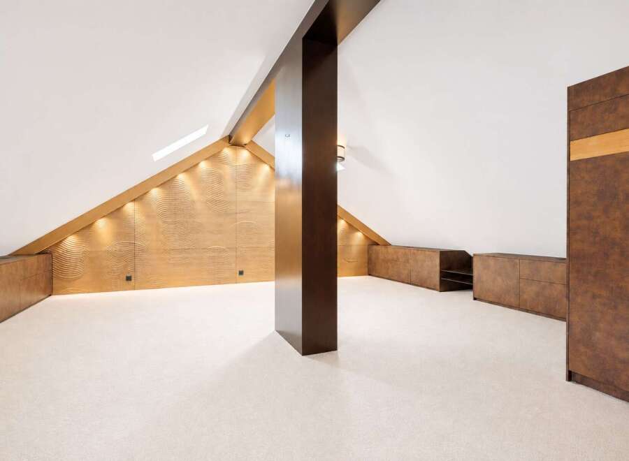 Discover this unique attic space, featuring a striking wave-patterned accent wall illuminated by warm accent lighting.