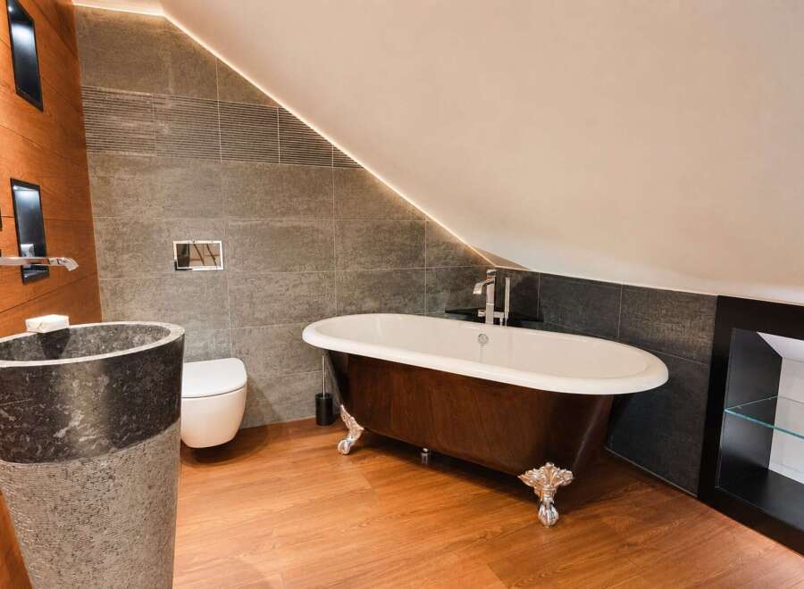Experience luxury in this stunning bathroom featuring a freestanding clawfoot tub with a rich wood finish and elegant silver feet.