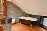 Experience luxury in this stunning bathroom featuring a freestanding clawfoot tub with a rich wood finish and elegant silver feet.