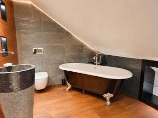 Experience luxury in this stunning bathroom featuring a freestanding clawfoot tub with a rich wood finish and elegant silver feet.