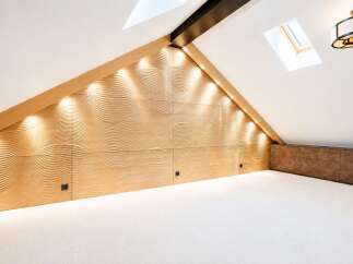 Experience modern luxury in this unique attic bedroom, featuring a stunning wave-patterned wood accent wall illuminated by ambient lighting.