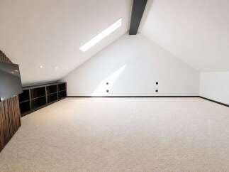 Discover this spacious attic room, perfect for a home theater or entertainment space.