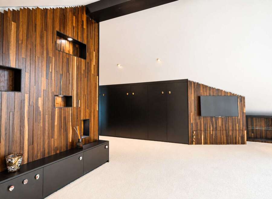 Experience modern luxury in this spacious living area, featuring a striking accent wall with vertical wood paneling and integrated shelving.