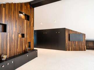 Experience modern luxury in this spacious living area, featuring a striking accent wall with vertical wood paneling and integrated shelving.