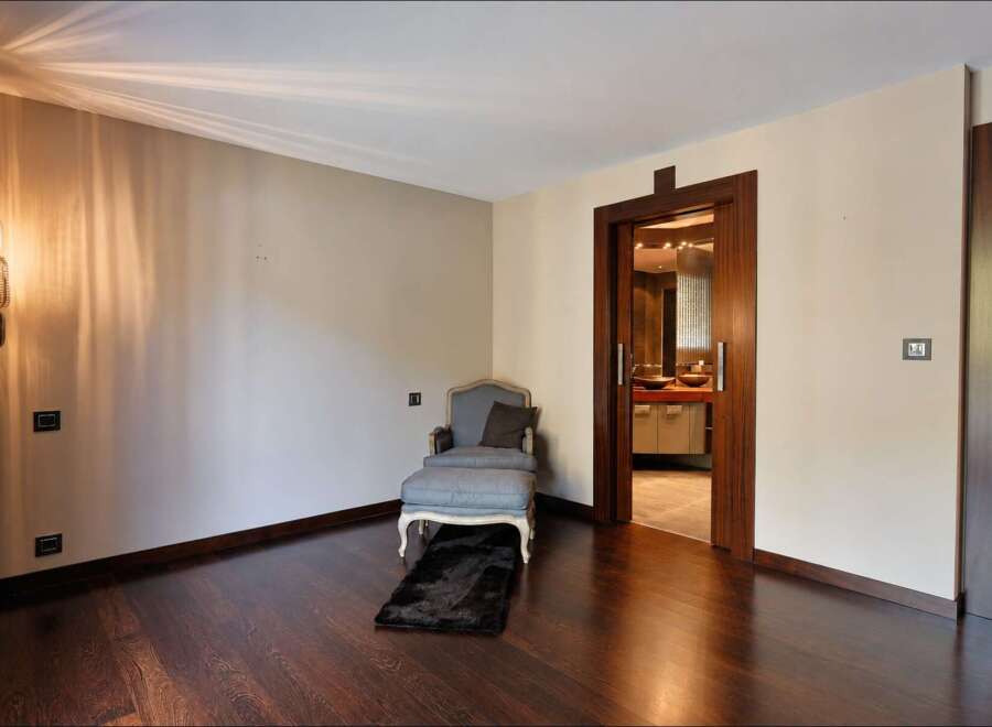 Step into a luxurious master suite featuring a comfortable chaise lounge and ottoman, perfect for relaxation.