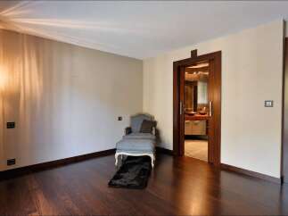 Step into a luxurious master suite featuring a comfortable chaise lounge and ottoman, perfect for relaxation.
