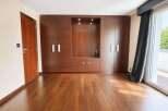 Experience modern living in this spacious room featuring a stunning floor-to-ceiling wooden wardrobe with integrated shelving and subtle lighting.