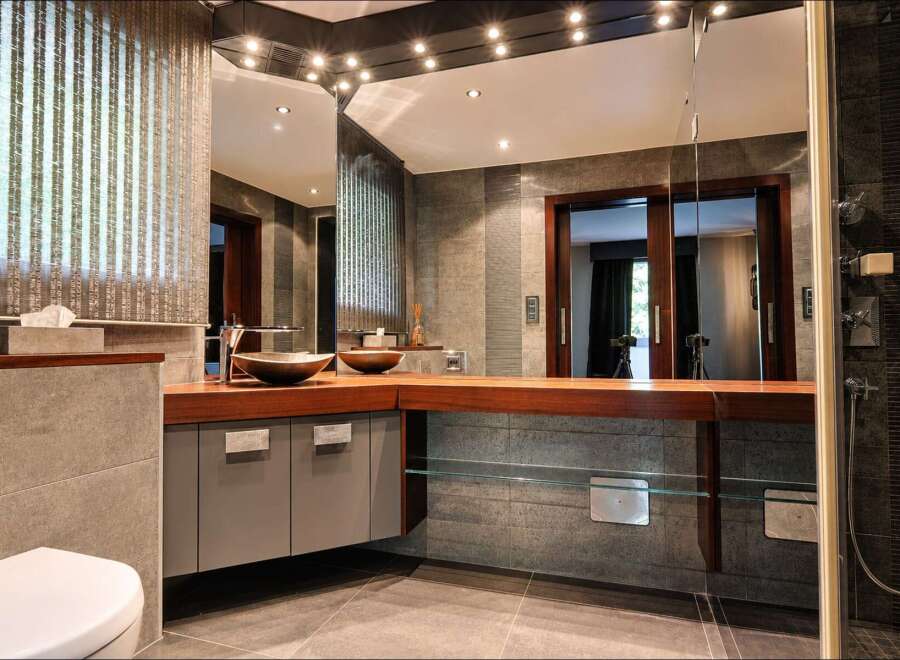 Experience luxury in this modern bathroom featuring a sleek vanity with dual vessel sinks and a rich wooden countertop.
