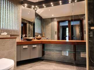 Experience luxury in this modern bathroom featuring a sleek vanity with dual vessel sinks and a rich wooden countertop.