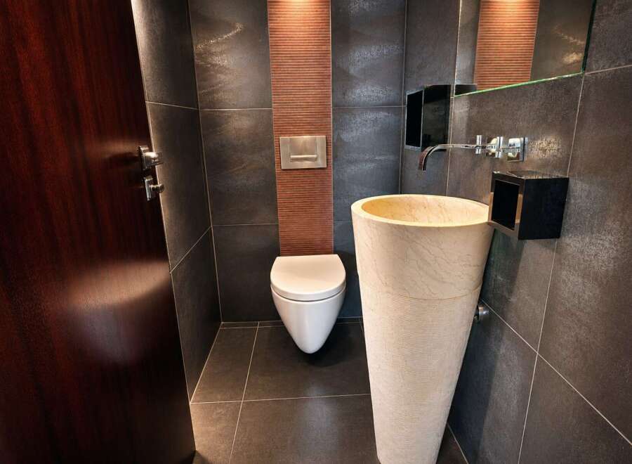 Experience modern luxury in this sleek bathroom featuring a striking pedestal sink and a wall-mounted toilet.