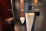 Experience modern luxury in this sleek bathroom featuring a striking pedestal sink and a wall-mounted toilet.
