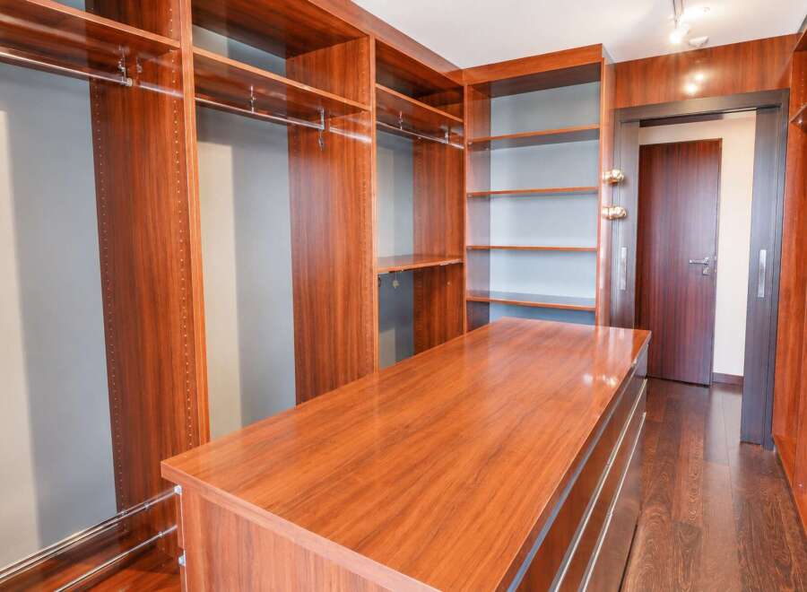 Step into this luxurious walk-in closet, featuring rich cherry wood cabinetry and ample shelving for all your storage needs.