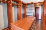 Step into this luxurious walk-in closet, featuring rich cherry wood cabinetry and ample shelving for all your storage needs.