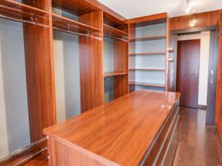 Step into this luxurious walk-in closet, featuring rich cherry wood cabinetry and ample shelving for all your storage needs.