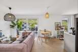 Experience modern living in this bright and airy open-plan space, featuring a stylish pink corduroy sofa and a round dining table perfect for intimate gatherings.