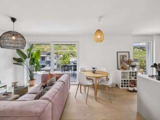 Experience modern living in this bright and airy open-plan space, featuring a stylish pink corduroy sofa and a round dining table perfect for intimate gatherings.