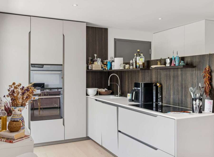 Discover this modern kitchen featuring sleek white cabinetry and integrated appliances, including a built-in oven.