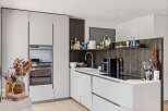 Discover this modern kitchen featuring sleek white cabinetry and integrated appliances, including a built-in oven.