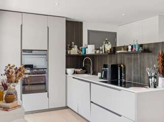 Discover this modern kitchen featuring sleek white cabinetry and integrated appliances, including a built-in oven.
