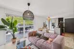 Experience modern living in this stunning apartment featuring a spacious open-plan living area with a plush pink sofa and a large glass coffee table.