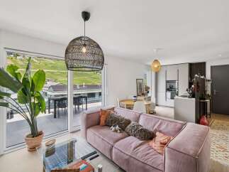 Experience modern living in this stunning apartment featuring a spacious open-plan living area with a plush pink sofa and a large glass coffee table.