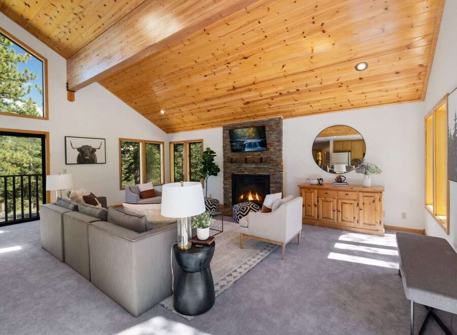 Experience rustic charm in this spacious living room, featuring a soaring vaulted wood-beamed ceiling and a striking stone fireplace.