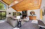 Experience rustic charm in this spacious living room, featuring a soaring vaulted wood-beamed ceiling and a striking stone fireplace.