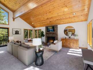 Experience rustic charm in this spacious living room, featuring a soaring vaulted wood-beamed ceiling and a striking stone fireplace.