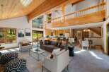 Experience rustic charm and modern comfort in this spacious living area, featuring a soaring wood-beamed ceiling and abundant natural light pouring in through large windows.