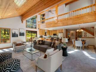 Experience rustic charm and modern comfort in this spacious living area, featuring a soaring wood-beamed ceiling and abundant natural light pouring in through large windows.