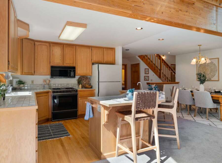 This spacious kitchen features warm oak cabinetry and a convenient island with bar seating, perfect for casual dining or entertaining.