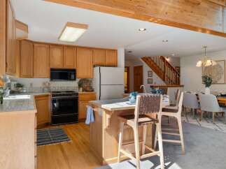This spacious kitchen features warm oak cabinetry and a convenient island with bar seating, perfect for casual dining or entertaining.