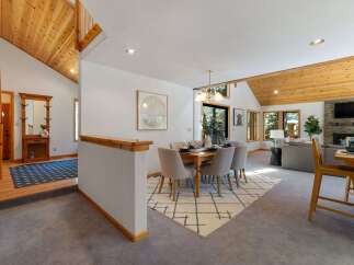 Experience the warmth of this inviting dining area, featuring a stylish wooden table set for six, complemented by comfortable upholstered chairs and a modern geometric rug.
