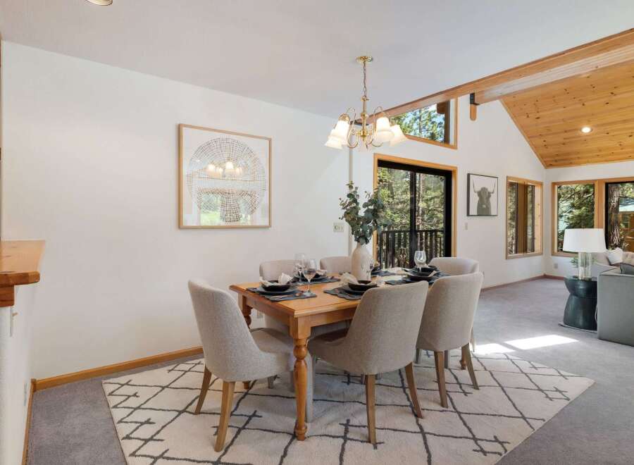 Experience cozy dining in this charming space, featuring a rustic wooden table set for six and comfortable upholstered chairs.