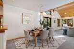 Experience cozy dining in this charming space, featuring a rustic wooden table set for six and comfortable upholstered chairs.